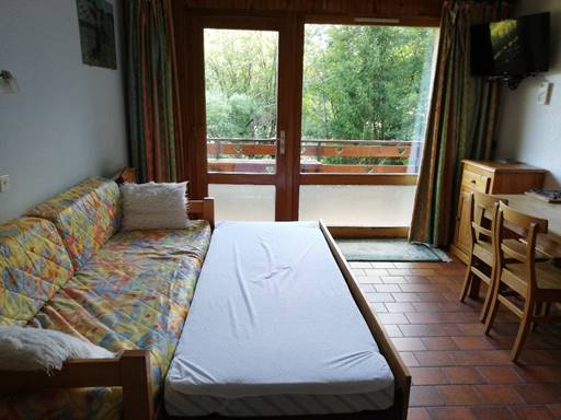 A view of a living room with a bed and a window

Description automatically generated
